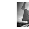 Black-and-white photography in "Sailboats" by Schiffer Publishing, Ltd. captures a classic sailboat with sunlit sails gliding across the water against a cloudy sky, reminiscent of Michael Kahn's evocative style.