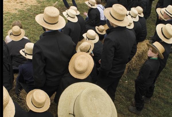 Seen from above, people and children in black clothing and straw hats sit on hay bales, reflecting Amish life in Lancaster County—featured on the "Faces of Lancaster County Postcards" by Schiffer Publishing, Ltd.