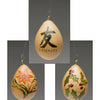 Three egg-shaped gourd ornaments from "Making More Gourd Ornaments" by Schiffer Publishing, Ltd. hang against a gray background, featuring FRIENDS with a Chinese character, a red flower with leaves, and holly—perfect for festive decor.
