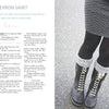 A person in a dark chevron skirt—made with Knitting for Little Sweethearts by Schiffer Publishing, Ltd.—black tights, and lace-up boots with gray knitted cuffs stands on wet pavement. Skirt knitting pattern instructions are shown on the left.