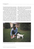 A man in blue kneels on grass, petting two white setters, with a white house and trees behind him. Featured: "The Real Ryman Setter: A History with Stories from the Appalachian Grouse Covers" by Schiffer Publishing, Ltd.