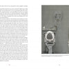 A two-page spread from “Demons” by Schiffer Publishing, Ltd.: The left page shows two-column text on exorcism techniques; the right depicts a bathroom with a raised toilet seat, toilet paper, shelf items, and a shower curtain—hinting at demon hunters.
