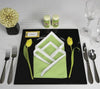 Set a chic table with silverware, glasses, a black plate, and a folded green and white napkin—framed by yellow tulips—as featured in Schiffer Publishing, Ltd.'s Creative Napkins and Table Settings. A name card and yellow arrangement complete the look.