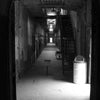 A black and white photo features a long, empty, decaying prison corridor at Eastern State Penitentiary—one of Philadelphia’s haunted places highlighted in Schiffer Publishing, Ltd.’s *Philadelphia Haunts*. Eerie light and barred doors set a chilling scene.