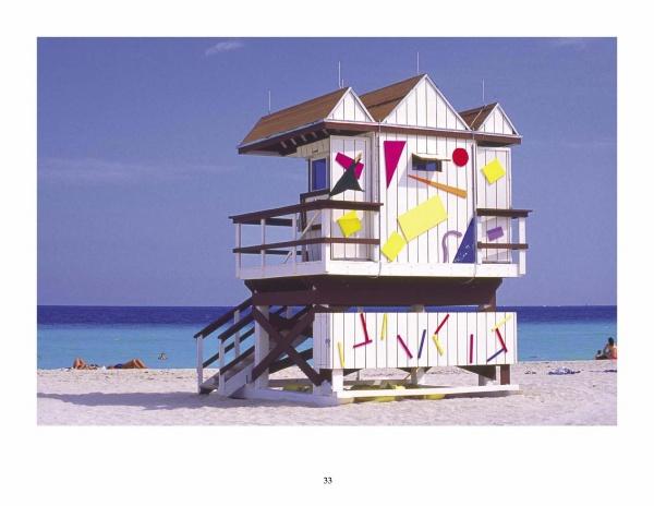 The South Beach Lifeguard Stations by Schiffer Publishing, Ltd. features a white stand with colorful geometric shapes on a sandy beach, turquoise ocean, and clear blue sky—ideal for capturing classic South Beach photography.