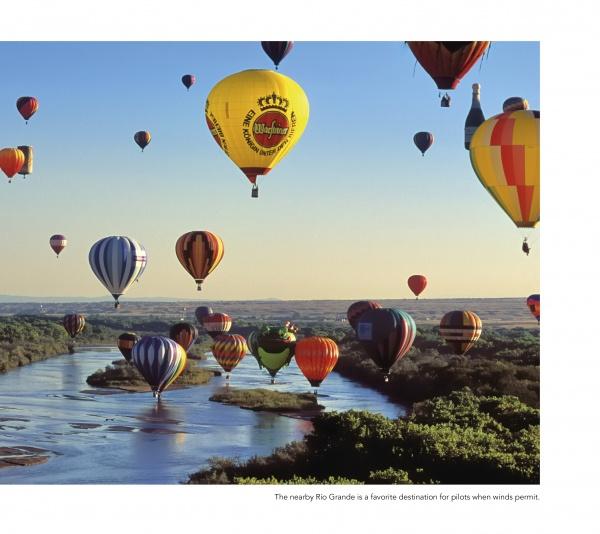 Experience the magic of the Albuquerque International Balloon Fiesta with "Balloons Over Albuquerque" by Schiffer Publishing, Ltd., featuring vibrant hot-air balloons soaring above a scenic river and lush landscape under clear blue skies.