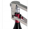 A close-up of the Screwpull corkscrew by Schiffer Publishing, Ltd. shows its lever mechanism uncorking a red wine bottle, with the opener attached securely to the bottle’s neck.