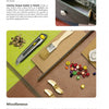 On a table sits The Great Book of Cardboard Furniture by Schiffer Publishing, Ltd., surrounded by paintbrushes, paper, and gold drawer pulls. The page features DIY furniture finishing tips and hardware inspiration.