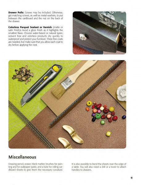 On a table sits The Great Book of Cardboard Furniture by Schiffer Publishing, Ltd., surrounded by paintbrushes, paper, and gold drawer pulls. The page features DIY furniture finishing tips and hardware inspiration.