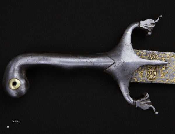 Close-up of a steel sword hilt with a curved handle and ornate crossguard from Weapons of Warriors by Schiffer Publishing, Ltd. The blade, inspired by historical swords, showcases gold patterns and calligraphy near the base against a black background.