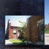 The cover of Lost in the Darkness by Schiffer Publishing, Ltd. shows a brick building with boarded windows and overgrown plants by the entrance. A clear sky is partly visible. The photo features a caption below and a dark textured border.