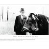 A black-and-white photo from "Pickled Punks and Girlie Shows" (Schiffer Publishing, Ltd.) shows a man in a suit with a two-headed cow titled “DOLLY The Only Live 2 Headed Cow in the World,” set against a field and fence.