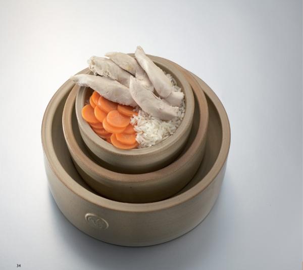 Cooking for Dogs by Schiffer Publishing, Ltd. features recipes like a layered clay pot with cooked chicken, white rice, and carrots—a great homemade dog treat to boost your dog's nutrition.