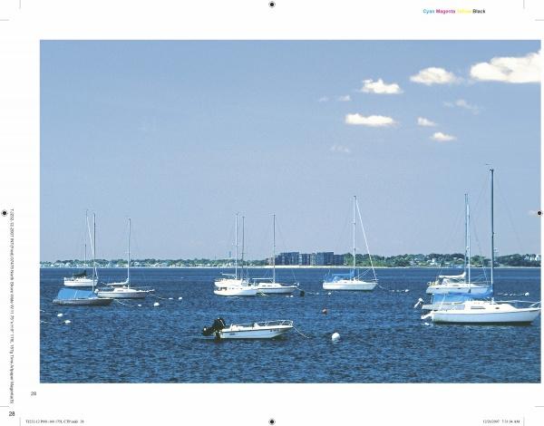 Sailboats and small motorboats rest on calm blue water beneath a clear sky, with distant buildings and trees, captured in classic North Shore Massachusetts style from "North Shore Wide" by Schiffer Publishing, Ltd.