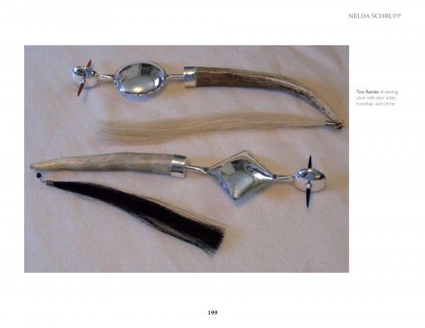 Two silver and deer antler rattles from "Masters of Contemporary Indian Jewelry" by Schiffer Publishing, Ltd. rest on a white surface—one with a circular top and light tassel, the other with a diamond-shaped top and dark tassel.