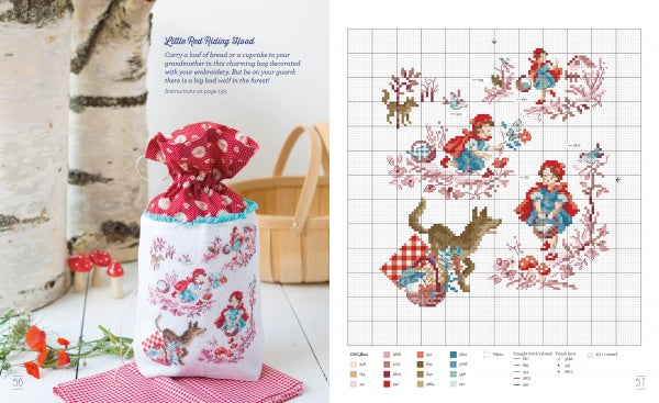 A drawstring bag with Véronique Enginger’s Little Red Riding Hood cross stitch from Schiffer Publishing, Ltd.’s "Fables & Fairy Tales to Cross Stitch" sits on a table beside flowers, mushrooms, and the matching pattern chart.