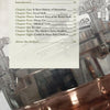 A page from Coulter & Payne Farm Distillery's 101 Uses for Moonshine by Schiffer Publishing, Ltd. shows the table of contents over a grayscale image of a copper still, with chapters on moonshine history, social skills, recipes, and farm-to-bottle trends.