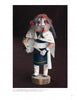 A carved female figure inspired by Hopi Kachinas, wearing a white shawl and dark garment with white trim, fur hair, red and white face paint, holding sticks. Product: Hopi Kachinas by Schiffer Publishing, Ltd.