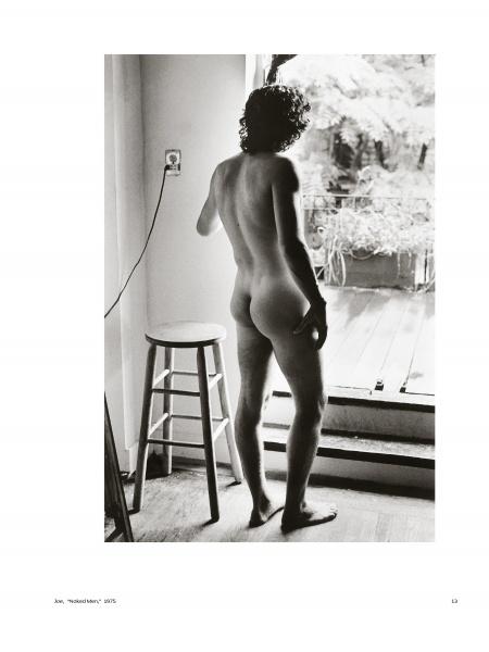 Inspired by Vivienne Maricevic, "She Shoots Men" by Schiffer Publishing, Ltd. features black and white male nude photography—a nude man indoors by a wooden stool, gazing through an open door at sunlit patio plants in an intimate moment.