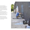 Two graffiti artists create street art on a black wall outdoors in daylight. One kneels close, with sunglasses and gloves, while the other works farther down. A block quote about graffiti and public opinion appears on the left. Product: 2Create by Schiffer Publishing, Ltd.