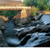 Timeless Crossings" by Schiffer Publishing, Ltd. features a covered wooden bridge over a rocky river and waterfall amid lush trees, with sunlight casting scenic shadows—an ideal capture for fans of rural Vermont and bridge photography.