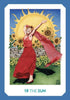 A joyful woman in a red dress dances before sunflowers and a stone wall as the bright sun shines behind her. The card, titled 19 THE SUN, radiates positive energy in the Gaian Tarot by Schiffer Publishing, Ltd.