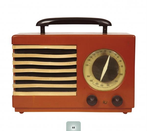 The Schiffer Publishing, Ltd. Retro Radio features a vintage red design with a black handle, gold speaker grille, large tuning dial, and two black front knobs—ideal for classic radio enthusiasts.