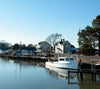 The book "Eastern Shore Perspectives" by Schiffer Publishing, Ltd. captures a white fishing boat docked on calm waters beside wooden piers, with houses and trees along Maryland’s Eastern Shore on a clear blue day.