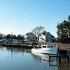 The book "Eastern Shore Perspectives" by Schiffer Publishing, Ltd. captures a white fishing boat docked on calm waters beside wooden piers, with houses and trees along Maryland’s Eastern Shore on a clear blue day.