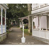 A quiet, tree-lined path in Oak Bluffs runs between white houses with porches and flowers—a perfect scene captured in "Oak Bluffs on the Vineyard" by Schiffer Publishing, Ltd., ideal for any Martha’s Vineyard souvenir book.