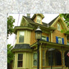 A charming Victorian cottage with ornate trim and a two-story bay window, often seen on Cape May Walking Tours by Schiffer Publishing, Ltd., stands behind a streetlamp and green trees on a bright day.