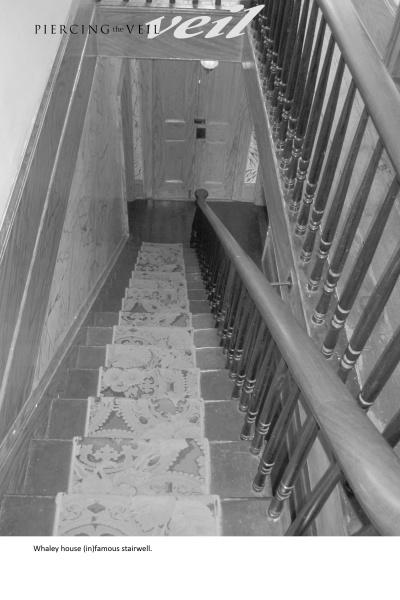 Black-and-white photo of a narrow, carpeted stairwell with wooden handrails, leading to a closed door. Text reads "Piercing the Veil," a book from Schiffer Publishing, Ltd., featuring the haunted Whaley House of San Diego.