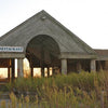 “Gone But Not Forgotten” by Schiffer Publishing, Ltd. captures the haunting allure of an abandoned restaurant, sunlight streaming through its open walls as overgrown weeds and faded signs reflect the lost charm of New England ghost towns.
