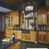 A spacious kitchen features elegant cabinets, black granite counters, a large arched window, and a barrel ceiling. An island set for two displays cake, fruit, wine—showcasing design tips from The Kitchen Guide by Schiffer Publishing, Ltd.