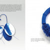 A two-page spread from Artistry in Fiber, Vol. 3 by Schiffer Publishing, Ltd. showcases blue and white contemporary earrings and a matching wearable fiber art necklace with blue beads; the artist’s photo and bio are in the top left corner.