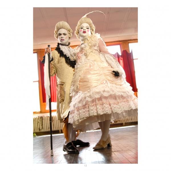 Two people in ornate 18th-century costumes and white wigs pose indoors, their theatrical makeup and outfits reflecting the creative essence of JoJo Baby and performance art featured in "Getting into Face" by Schiffer Publishing, Ltd.
