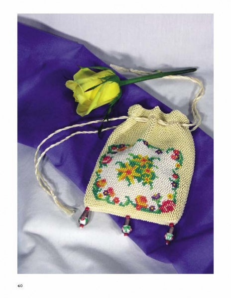 The book "Knitting Beaded Purses" by Schiffer Publishing, Ltd. is displayed on purple and white fabric next to a yellow artificial rose.