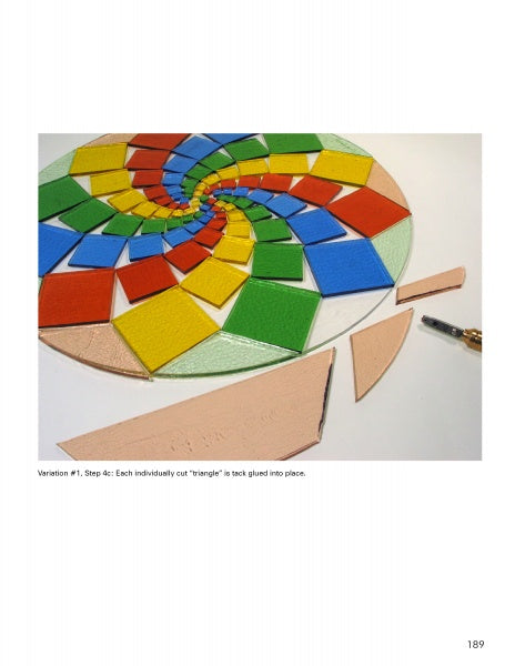 A circular mosaic in progress shows vibrant ceramic triangles in a spiral, inspired by "Glass Art From the Kiln" from Schiffer Publishing, Ltd. Tile-cutting tools and beige pieces add contrast to the developing design.