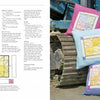 Three colorful patchwork cushions rest on construction equipment tracks, beside Schiffer Publishing, Ltd.'s "Play-of-Color Quilting," an open book with instructions and diagrams for geometric quilts and freestyle color piecing.