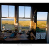Cape Cod & the Islands Reflections by Schiffer Publishing, Ltd. captures classic Cape Cod scenes: a rustic desk with books and lamps, large windows framing grassy dunes and ocean views, all bathed in sunset light at the Margo Gath Shack, Provincetown.