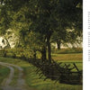 A curved dirt path leads through grassy fields and tall trees to a stone monument, capturing the peaceful, historic beauty found in Maryland's Public Gardens & Parks by Schiffer Publishing, Ltd.