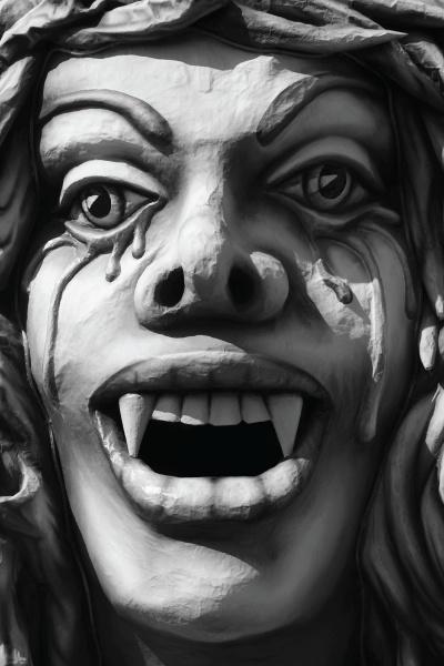 A close-up of a carved face with wide eyes, pointed fangs, and dramatic tears, echoing the fantastical figures in "Strange Minnesota Monsters" by Schiffer Publishing, Ltd., depicted in bold black and white.