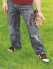 A person in ripped jeans and sneakers stands on grass, gently holding a baby squirrel—an image fitting for "Squirrel Rescue" by Schiffer Publishing, Ltd., a perfect children's book about wildlife rescue.
