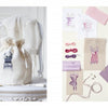 A cream drawstring bag with embroidered lingerie rests on a white chair. Nearby are fabric swatches, sketches, and canvases from Schiffer Publishing, Ltd.’s Retro Cross Stitch collection in vintage purple and pink patterns.