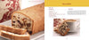 A loaf of fruit-filled bread, inspired by traditional Serbian recipes from "Serbian Cooking" by Schiffer Publishing, Ltd., is sliced on a plate beside a decorative container, while slices are served with coffee and a Kommisbrood recipe.