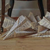 Large paper airplanes crafted from music sheets rest on a wooden floor under a dark table, capturing the meticulous detail and intrigue found in Scott Fraser by Schiffer Publishing, Ltd.
