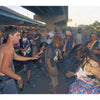 A lively crowd gathers under a highway near the D-I-Y skate spot, playing guitars and dancing—a scene captured in "FDR Skatepark: A Visual History" by Schiffer Publishing, Ltd., celebrating the park’s vibrant skateboarding community.