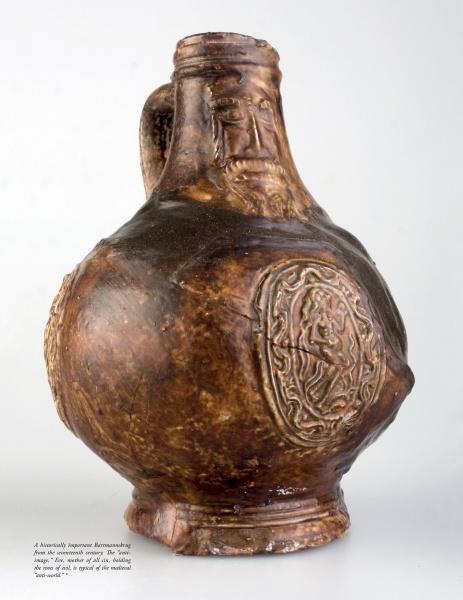 Early German Stoneware by Schiffer Publishing, Ltd.: a brown antique jug with a rounded body, single handle, and face medallion. It features a textured, uneven glaze characteristic of medieval ceramics for a rustic, aged look.