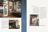 A book spread from "Passion for Primitives" by Schiffer Publishing, Ltd. shows rustic, sunlit interiors with wooden beams; the left page features a dining area and fireplace, the right a hallway and text about minimalist decor.