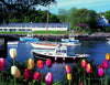 Colorful tulips frame a classic New England scene with boats on calm water and buildings along the shore beneath a clear sky. "New England" by Schiffer Publishing, Ltd. beautifully captures this timeless landscape.